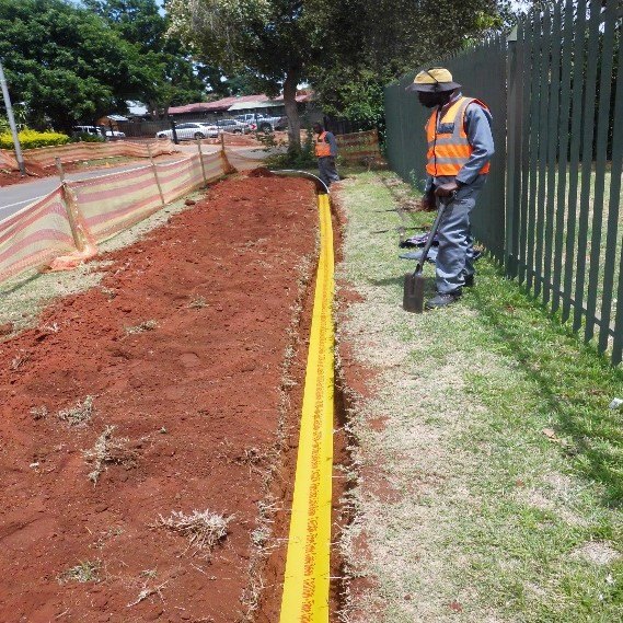 Fibre trench being dug beside a palisade fence